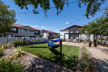 a yard with a hammock and houses in the background